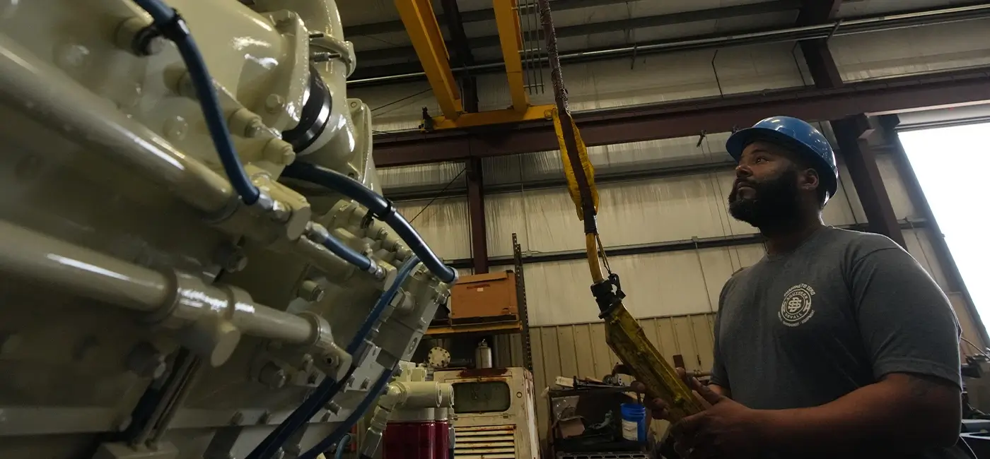 A Devall Diesel Technician preparing to lift a large, white diesel generator