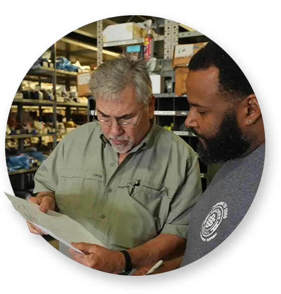 Two Devall Diesel employees looking over paperwork in a warehouse