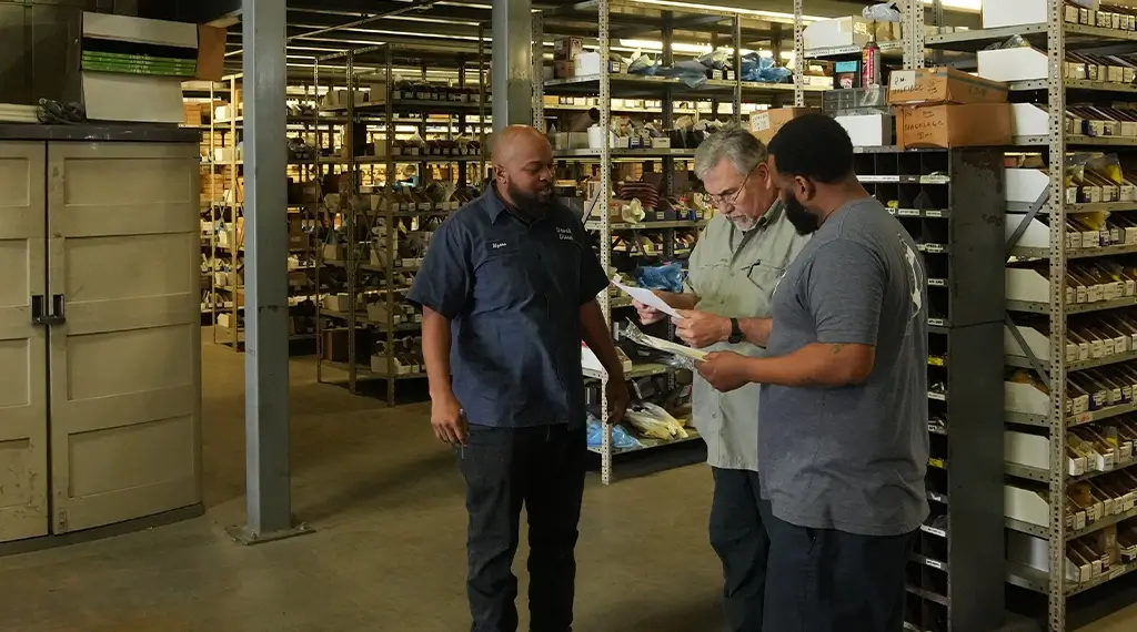 Three Devall Diesel employees looking over paperwork in a warehouse